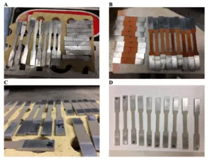 Figure 1. (A) Digital image of the waterjet cut HPDC A365 substrate/base material as reference specimens that therefore did not undergo cold gas dynamic spray (CGDS) processing. (B) Digital photo of the thinly coated and Cu CGDS processed A365 HPDC substrate specimens. (C,D) Digital images are similar to (B), where Ni and Ti were utilized as feedstock, respectively. For reference, the thickness of the base material (see (C) with the properly oriented specimen labeled “30”) was 2.5 mm before CGDS processing or postprocessing after that. Solution treatments we